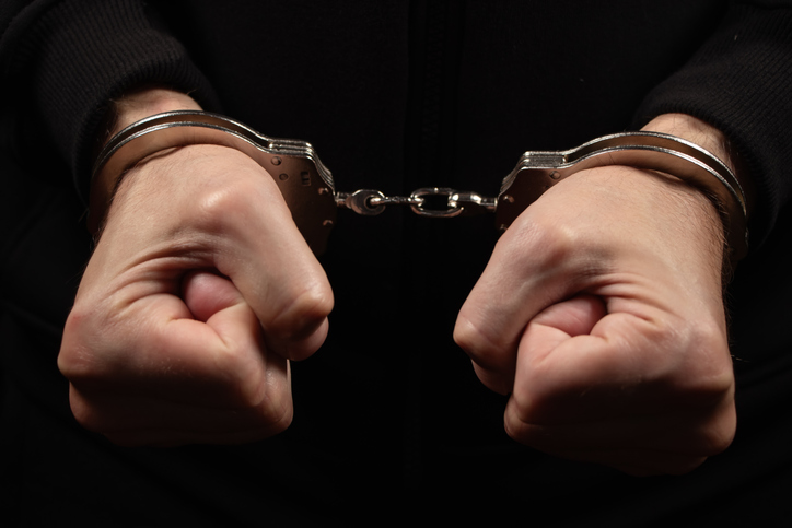 Male hands in handcuffs black background