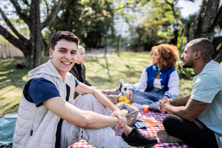 Portrait of a young man on a picnic with his friends at the public park