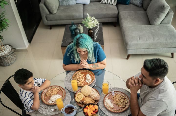 Family praying before eating lunch at home