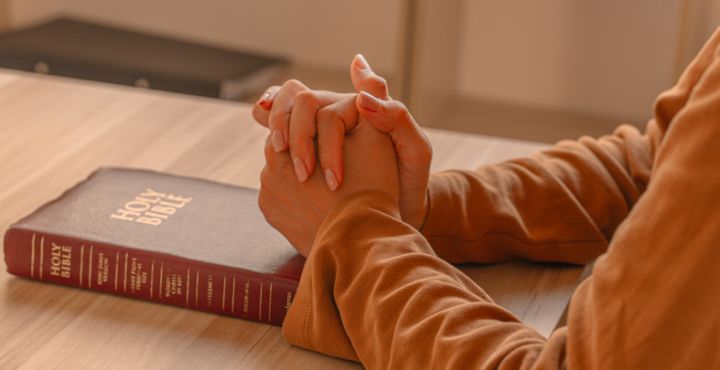 Close-up women christian read bible. Hands folded in prayer on a Holy Bible on wooden table.