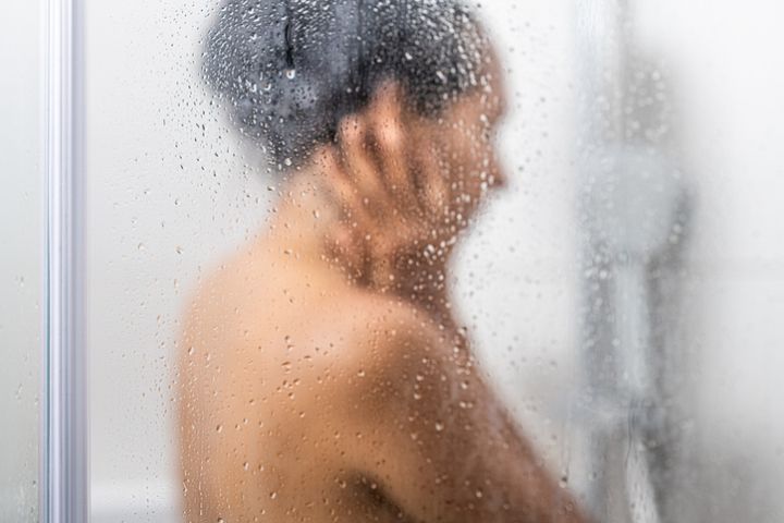 Woman showering behind fogged glass