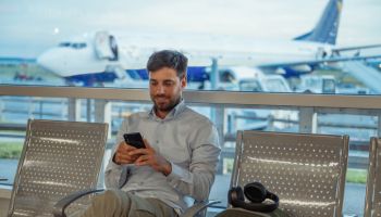 Young businessman at the airport waiting for the flight. Businessman using smart phone
