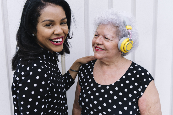 Happy senior woman wearing wireless headphones looking at daughter