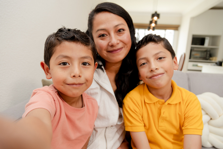 Portrait of mom and children at home-mom hugging hers two children in the living room of her house-single mother with her children-happy little family-Hispanic family