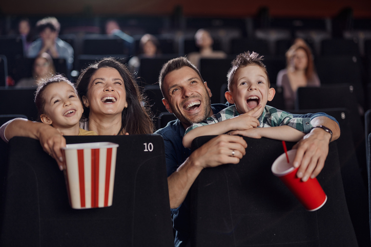 Young happy family watching a movie projection in theatre.