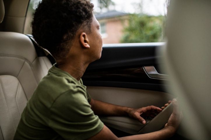 Tween boy looking out window in the back of car