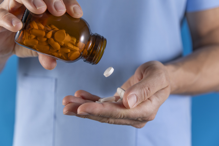 Hand with Pills Spilling Out of Bottle