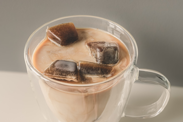 Frozen coffee cubes filled with milk in a glass cup