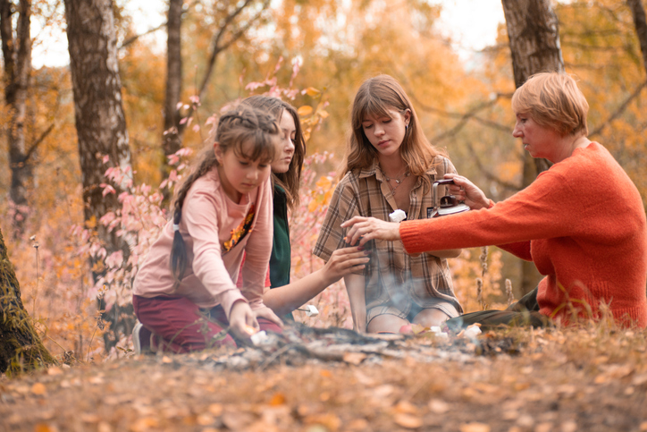 Girls family having fun at a cozy autumn campfire in a forest, making memories and building bonds