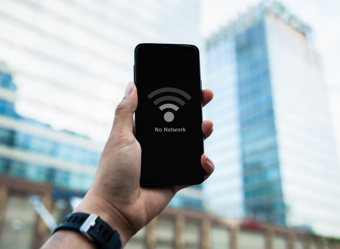 Close up of hand holding smart phone with low battery icon on screen. on blurred city building background