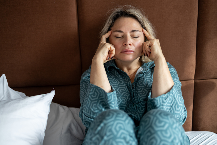 Mature woman suffering from a headache and cover her head with hands