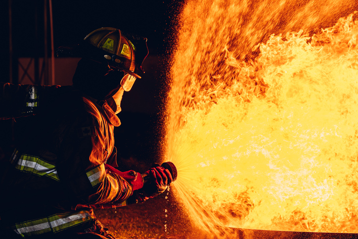 Firefighter Concept. Fireman using water and extinguisher to fighting with fire flame. firefighters fighting a fire with a hose and water during a firefighting training exercise