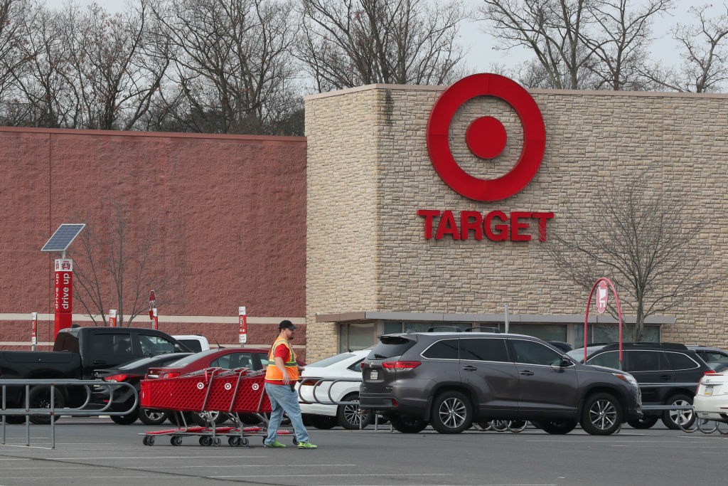 A worker retrieves shopping carts at the parking lot of a...