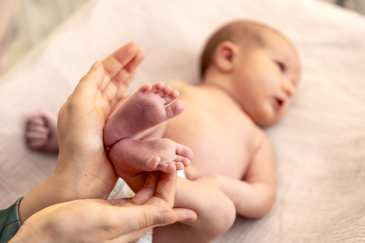Parent holding in the hands feet of newborn baby. Mom holding baby feet.