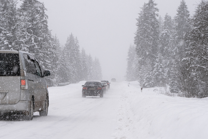 Car traffic navigating on the snowy road through the Forest during heavy snow.