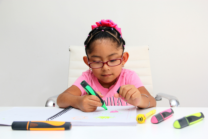 4-year-old Latina girl with autism spectrum disorder ASD like Asperger, Rett and Heller draws at a desk, plays with colors alone antisocial