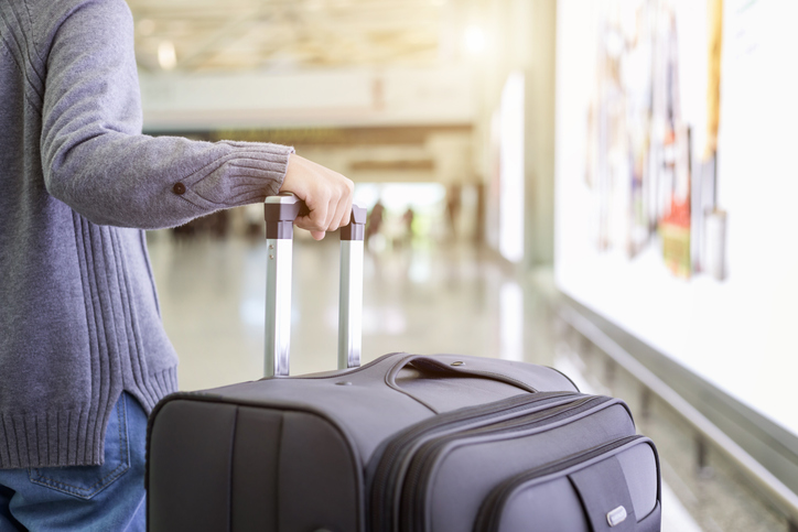 Midsection Of Woman Holding Suitcase At Airport