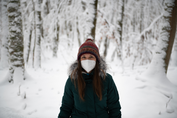 Woman in Winter Attire Standing in a Snowy Forest