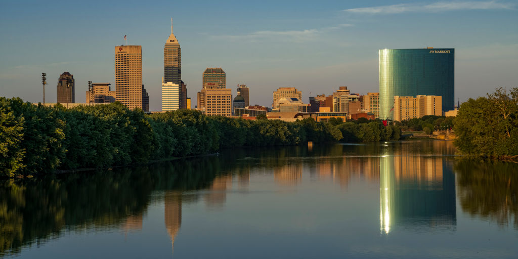Skyline view at sunset into dusk of Indianapolis buildings on White River reflect in water, Indiana