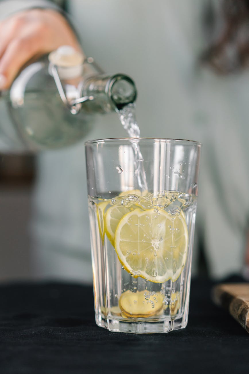 person pouring water on drinking glass