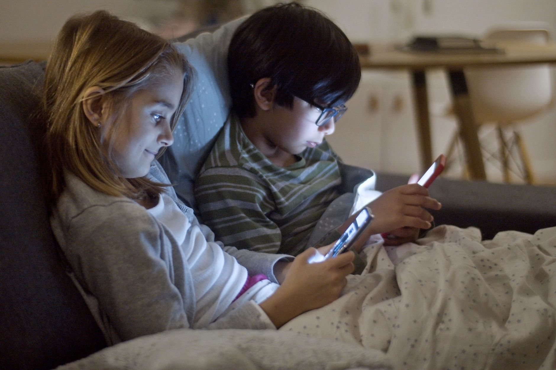 kids using gadgets while on a sofa bed