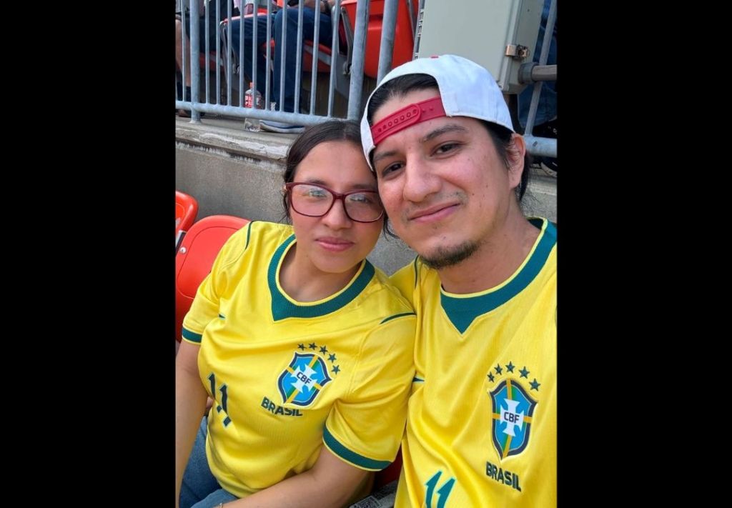 Two people wearing Brazil national team jerseys with "Brasil" text, smiling and posing together.