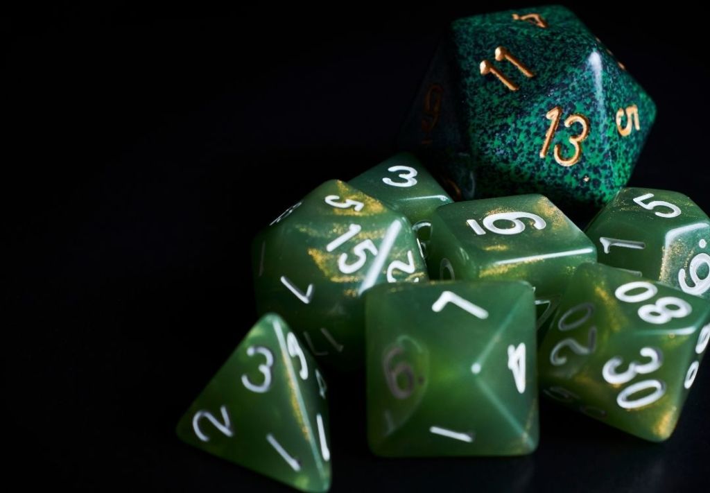 A collection of polyhedral dice in various shades of green, with numbers visible on their faces.