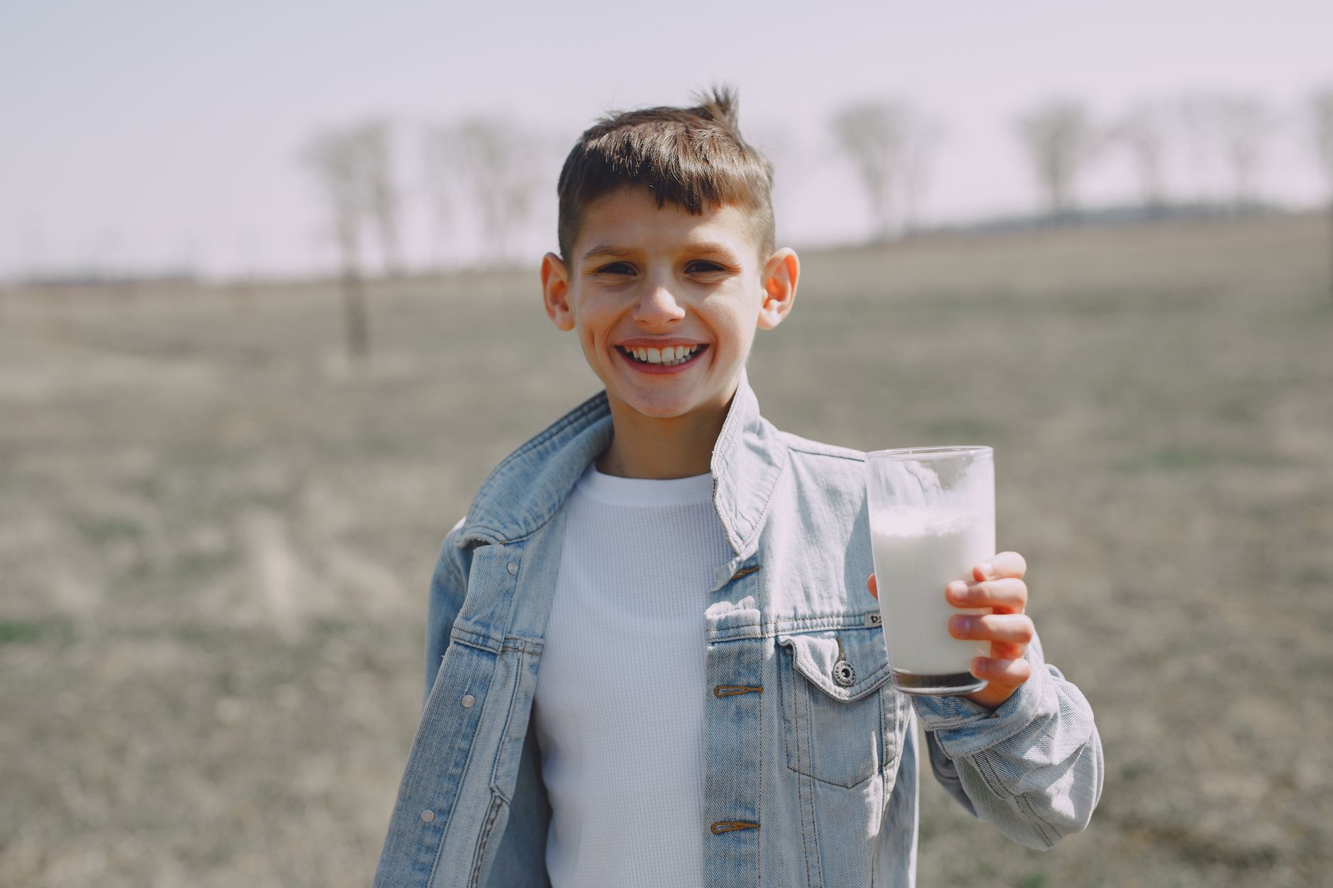 happy boy with glass of milk in countryside
