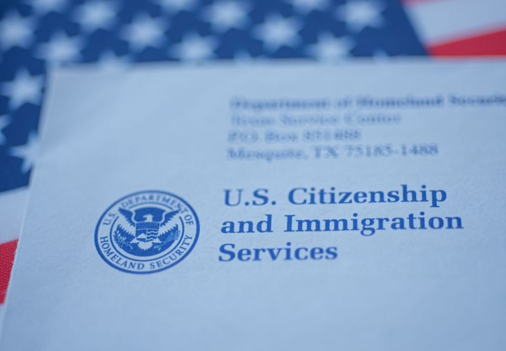 U.S. Citizenship and Immigration Services logo and address on an American flag background.