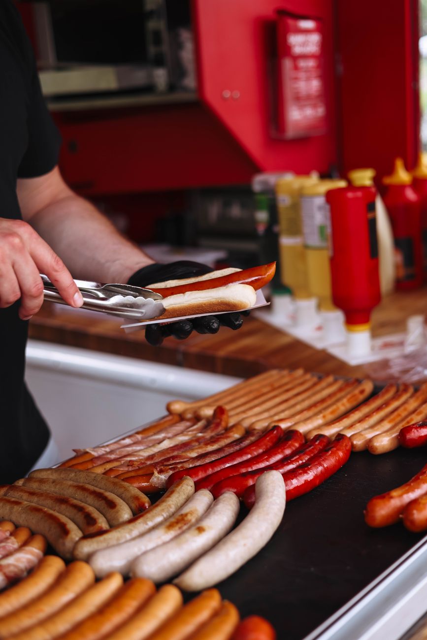 a man is cutting up hot dogs on a grill