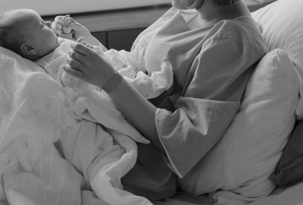 A newborn baby being held by a person in a medical setting.