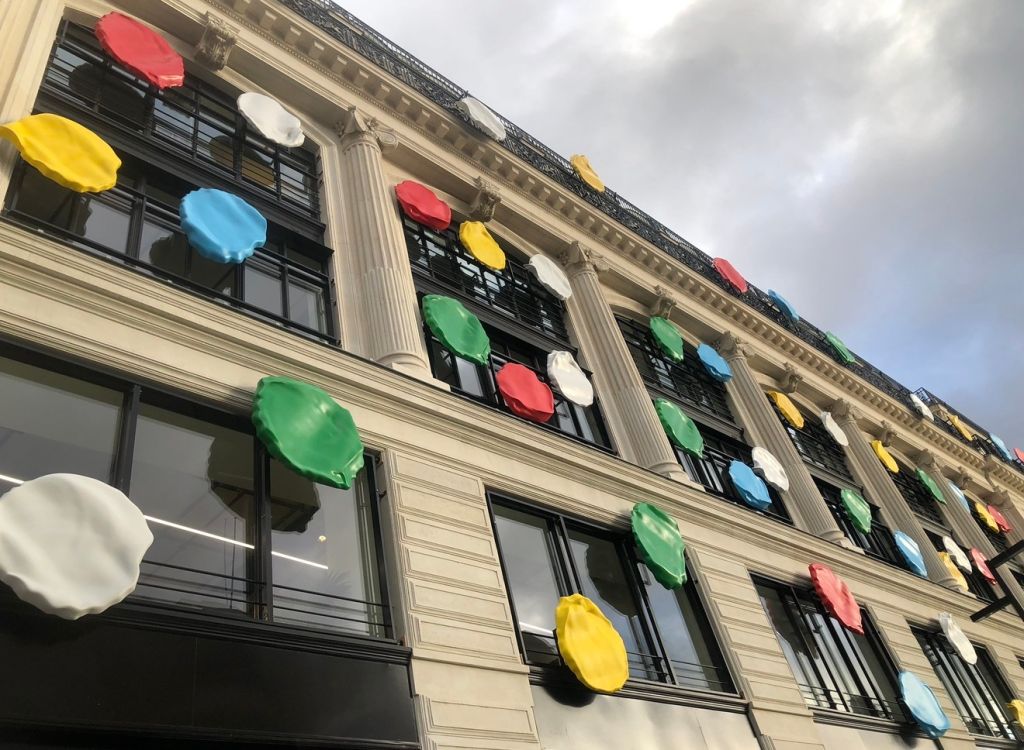 Colorful umbrellas hanging from the facade of a historic building with columns.